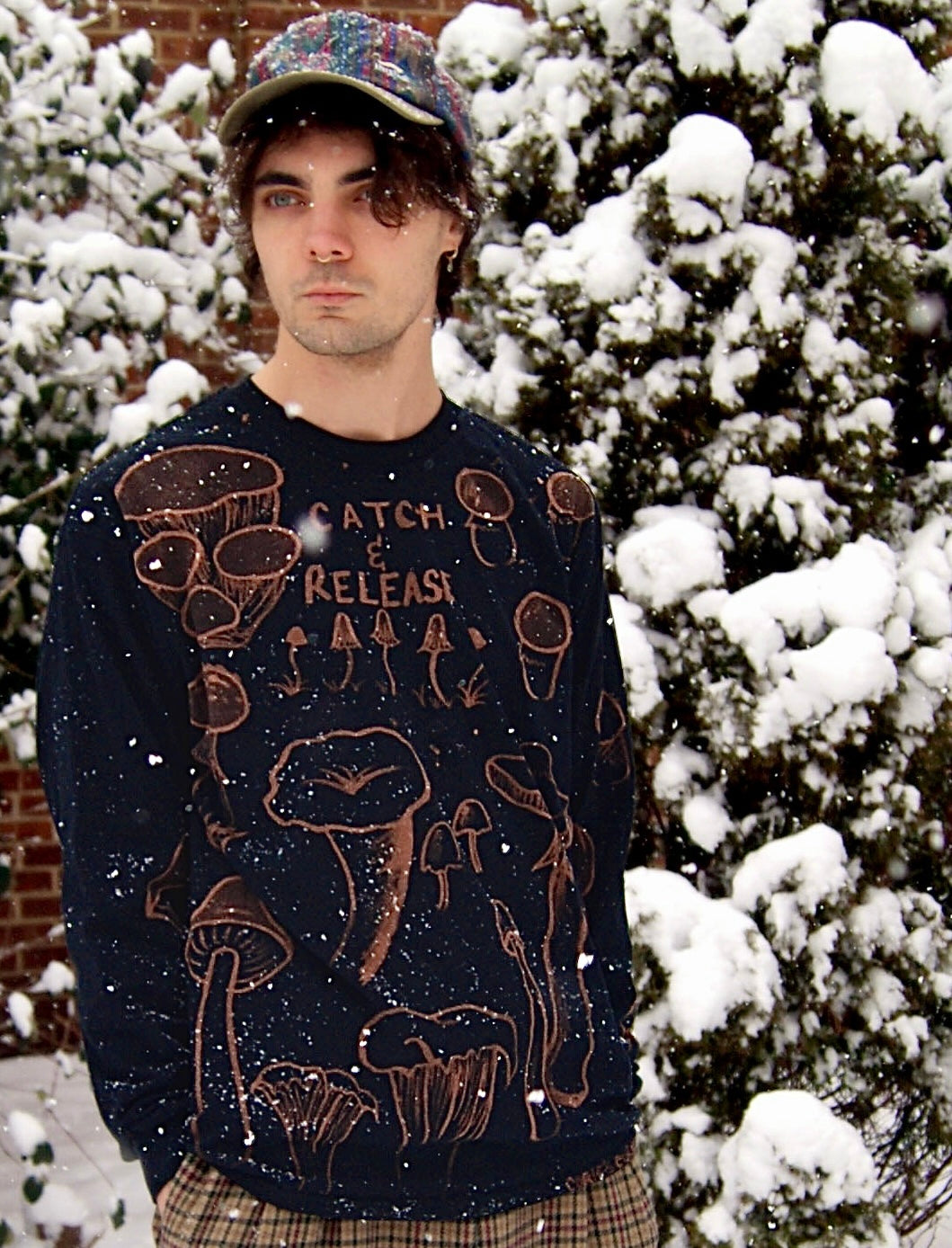Model wears one-of-a-kind painted long-sleeve tee with a design of different types of mushrooms & the words "Catch & Release"