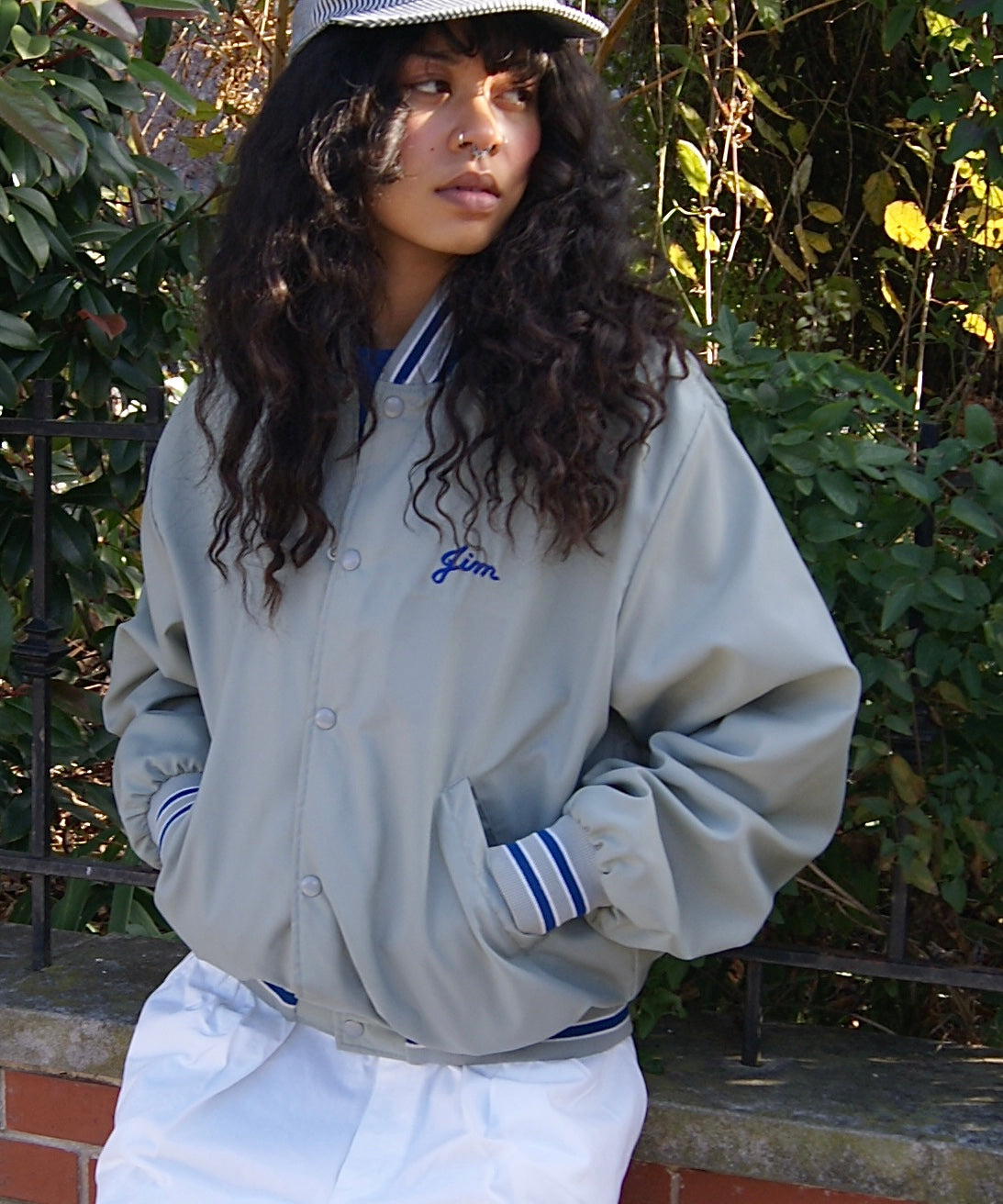 Model posing in front of greenery in vintage Bass Busters Club varsity Jacket.