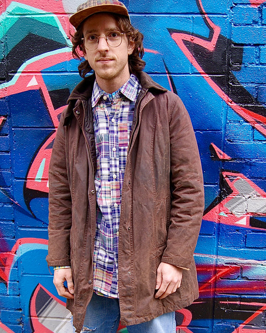 mid-length brown waxed canvas Barbour jacket with hood worn by male model