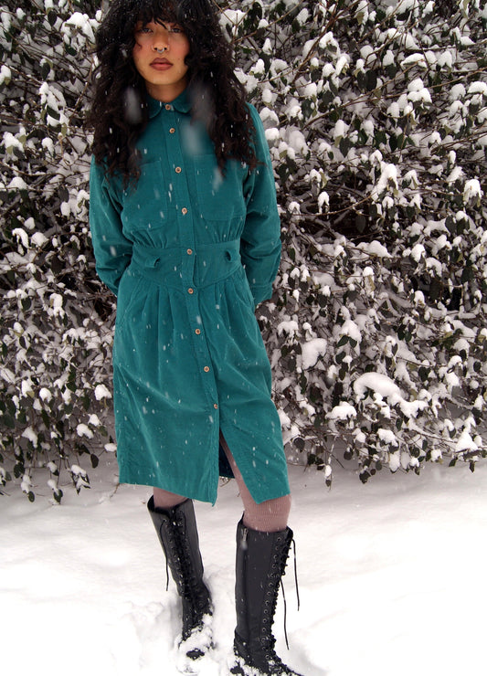 model wears green corduroy vintage long-sleeve dress in the snow